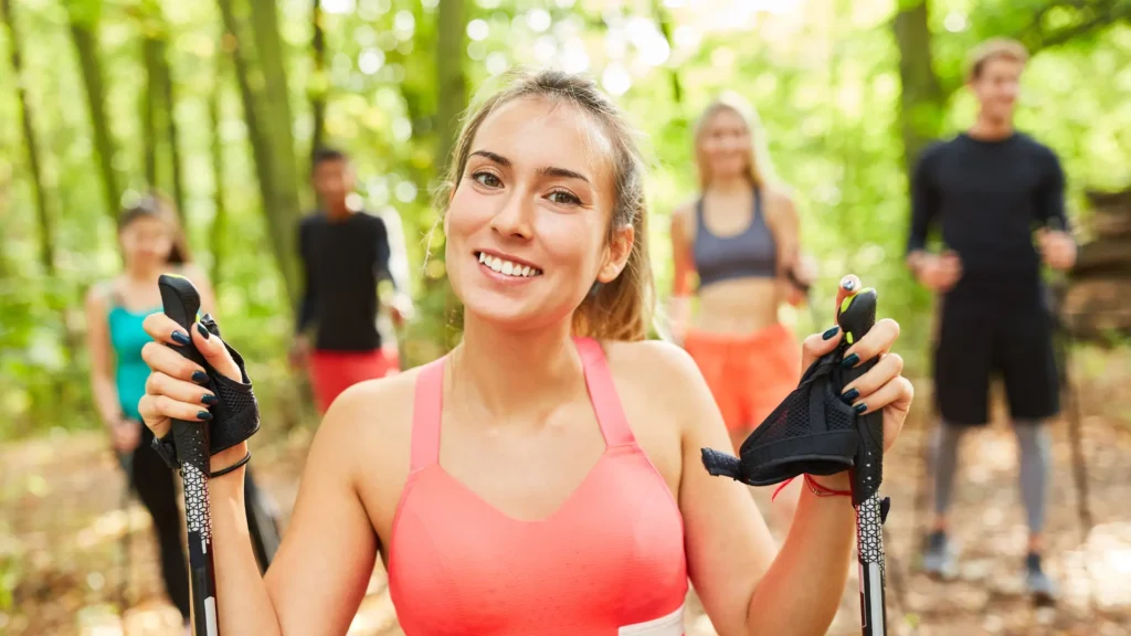 Erfolgreiche Nordic Walking Trainerin mit zufriedener Gruppe in der Natur